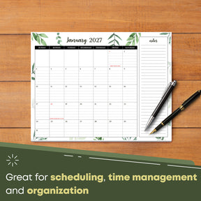 2027 desk calendar on a wooden desk with pens, January page with ruled day boxes