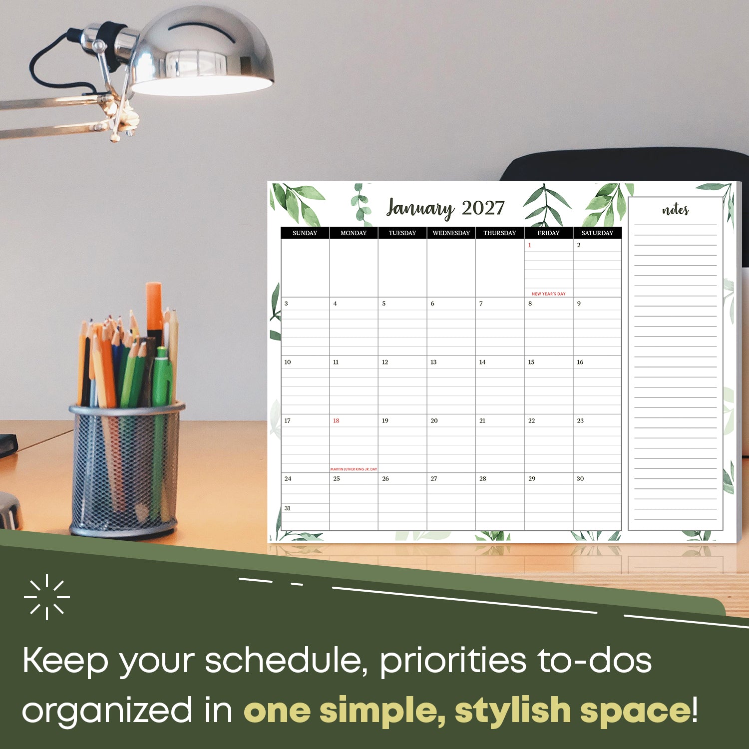 2027 desk calendar on an office desk next to a lamp and pencil cup