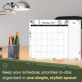 2027 desk calendar on an office desk next to a lamp and pencil cup